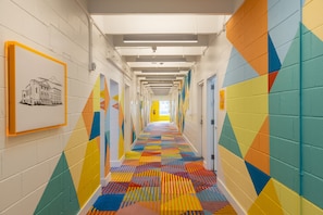 Ein farbenfroher Flur mit einem gemusterten Boden, weißen Wänden und geometrischer Wandkunst.