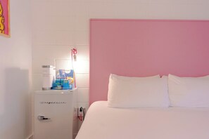 A bedroom with a bed, a white minibar, and a pink headboard. - The Gallatin (311) Colorful Boutique Hotel (Nashville)