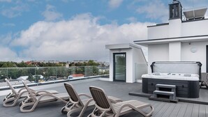Eine Dachterrasse mit Liegest ühlen, einem Whirlpool und einem modernen Gebäude im Hintergrund.