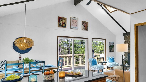 A spacious kitchen with a large island, a dining area with blue chairs, and a view of the outdoors.