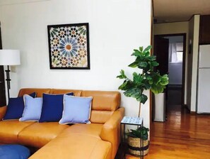 Relax in this stylish living room with a comfortable sofa, framed artwork, and a lush potted plant.