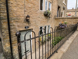 A stone building with a metal gate, a number plaque, and flower boxes.