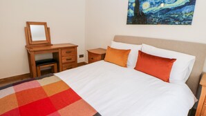 A neatly made bed with a colorful blanket, a wooden nightstand, a dresser, and a painting of a night sky on the wall. - The Old Cobblers (High Peak)