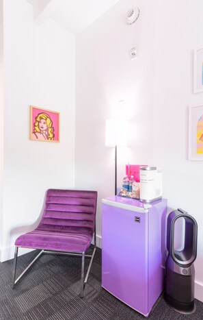 A purple chair, a white refrigerator, a lamp, and a vacuum cleaner in a room with white walls and a ceiling light. - The Gallatin (315) Only 3 miles to Broadway! (Nashville)