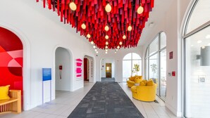 A hotel lobby with a central carpeted walkway, red hanging decor, and a yellow sofa. - The Gallatin (316) Colorful Boutique Hotel (Nashville)