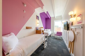 A room with a bed, a desk, a chair, a purple accent wall, and a window.