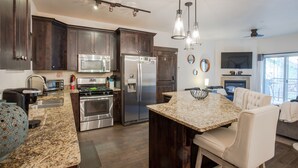 Una cocina moderna con armarios de madera oscura, electrodomésticos de acero inoxidable y una encimera de granito.