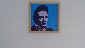 A room with a bed, a blue suitcase, and a framed artwork on the wall. - The Gallatin (319) - 2 miles to Nissan Stadium (Nashville)