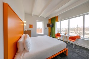 A hotel room with a large bed, a TV, a small table, two chairs, and a window with a view. - The Gallatin (320) Colorful Boutique Hotel! (Nashville)
