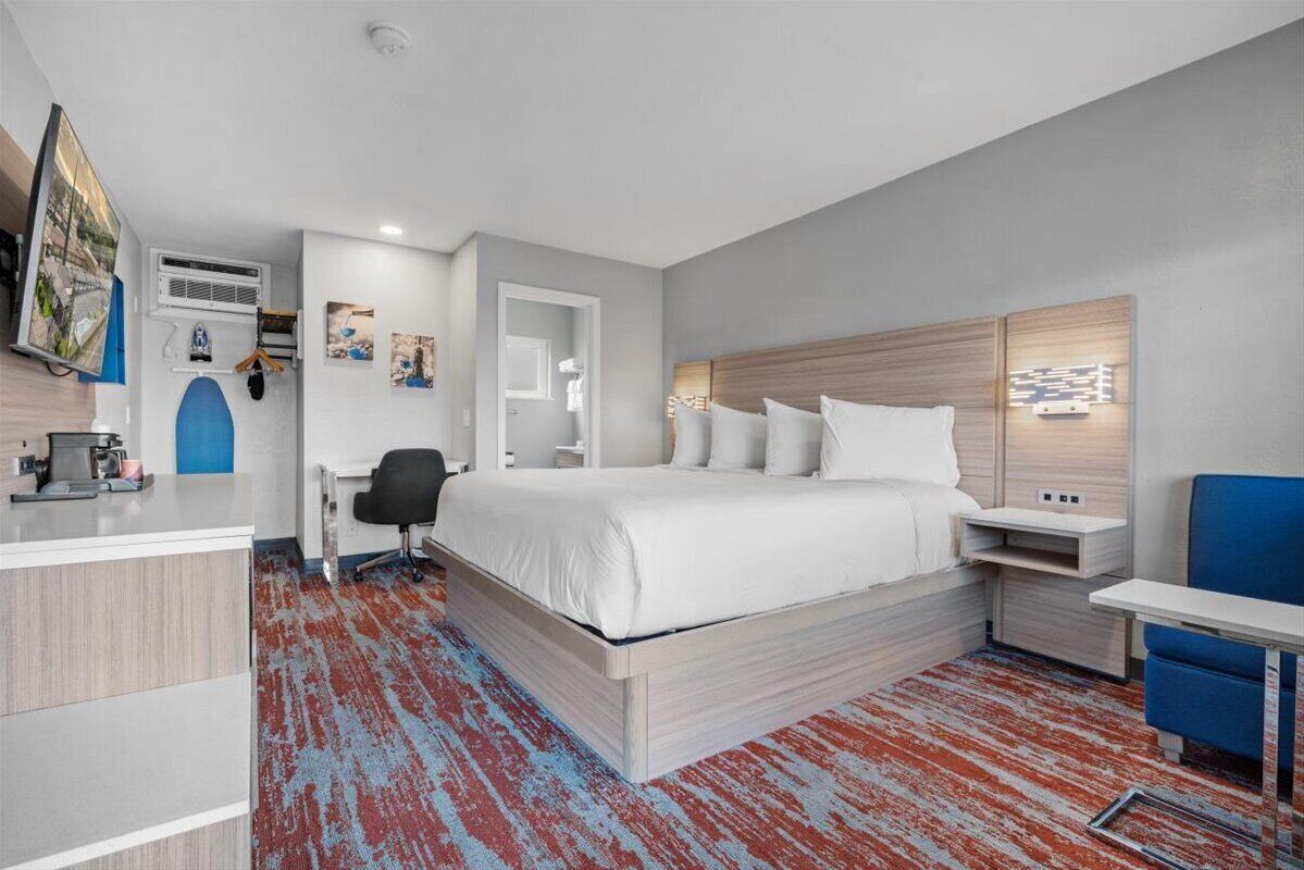 Una habitación de hotel moderna con una cama grande, un escritorio, una silla y un televisor.