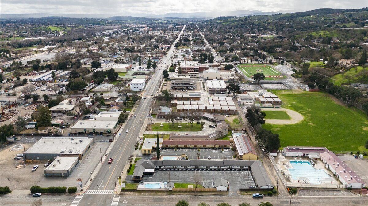 An aerial view of a commercial area with multiple buildings, a parking lot, and a sports field.