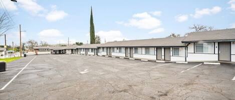Una hilera de habitaciones de motel con un estacionamiento al frente.