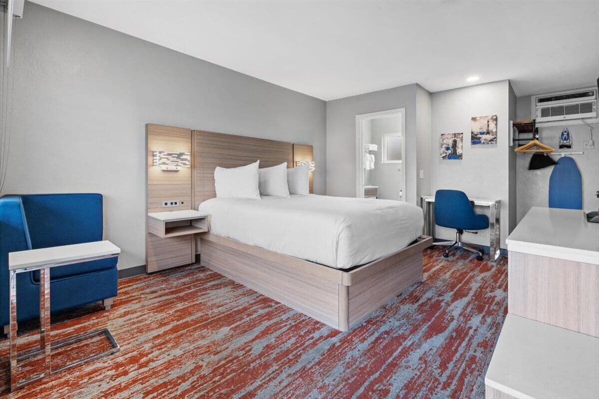 A modern hotel room with a large bed, a desk, and a chair.