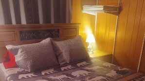A hotel room with a wooden headboard, a patterned bedspread, and a red throw pillow. - Beautiful cabin on the Manistee River (Mesick)