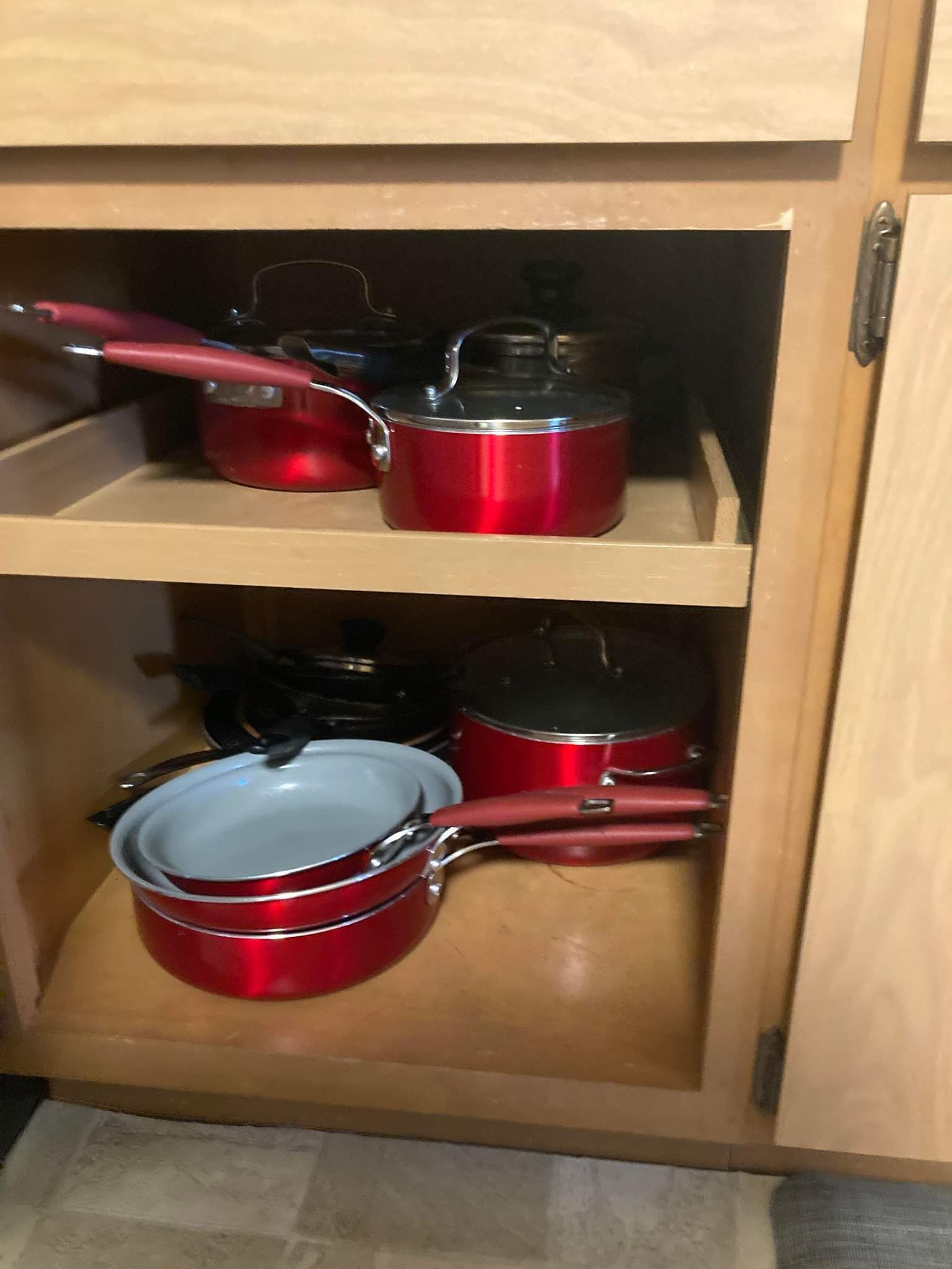 Un meuble en bois doté de deux étagères où sont rangés des ustensiles de cuisine rouges.