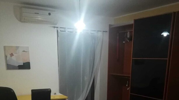 Une chambre comprenant un lit, un bureau, une chaise, un appareil de climatisation, une armoire et un rideau.