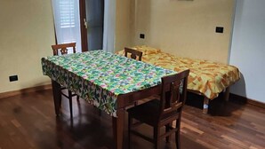 Un coin repas avec une table et des chaises en bois, une nappe à motifs et un luminaire suspendu.
