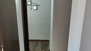 Un couloir étroit, doté d’un plancher en bois et d’une porte sur le côté gauche.