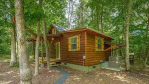 Une cabane en rondins avec un porche, entourée d’arbres.