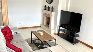 Ein Wohnzimmer mit Sofa, Couchtisch, Fernseher, Kamin und Dekoration.