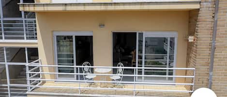 Un edificio de dos plantas con un balcón que tiene una mesa y sillas.