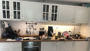 Una cocina con armarios blancos, un horno de acero inoxidable y una cafetera.