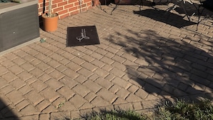Una casa de ladrillo con un patio, una zona de estar cubierta y una planta en maceta.