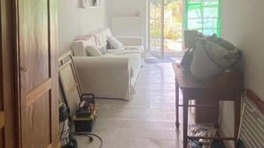 Una habitación amplia con un armario de madera, un sofá blanco y una mesa de comedor.