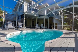 Una piscina con cubierta de madera, sillas de descanso y un patio techado.