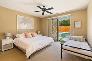 Relax in a spacious bedroom with a large bed, nightstands, and a ceiling fan, offering a serene view of the surrounding greenery.