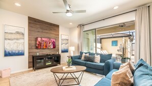 A modern living room with a blue sofa, a wooden coffee table, and artwork on the walls.