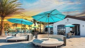 A poolside area with lounge chairs, umbrellas, and a bar/lounge named "Ti Casa".