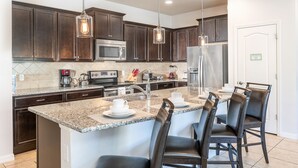 A modern kitchen with dark wood cabinets, stainless steel appliances, and a granite countertop.