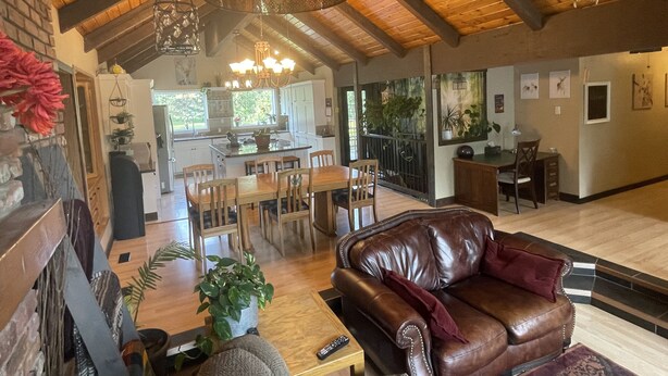 Amplia sala de estar con sofá de cuero, mesa de comedor de madera y cocina al fondo.