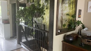 Una habitación con una escalera de madera, una planta colgante, un espejo y un escritorio con una computadora y una lámpara.