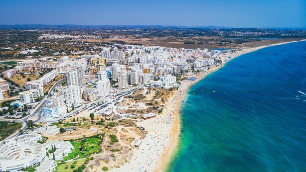 An aerial view of a coastal city with high-rise buildings, a beach, and a clear blue sea. - Arma O DE P RA Twins 2 by Homing (Lagoa)