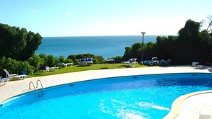 A swimming pool with a view of the ocean, surrounded by lounge chairs and a well-maintained lawn. - Arma O DE P RA Twins 2 by Homing (Lagoa)