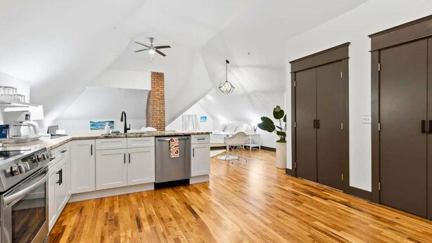 A modern kitchen with a central island, stainless steel appliances, and a wooden floor.