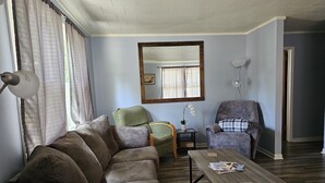 Un salon avec un canapé, des fauteuils, une table basse et un miroir au mur.