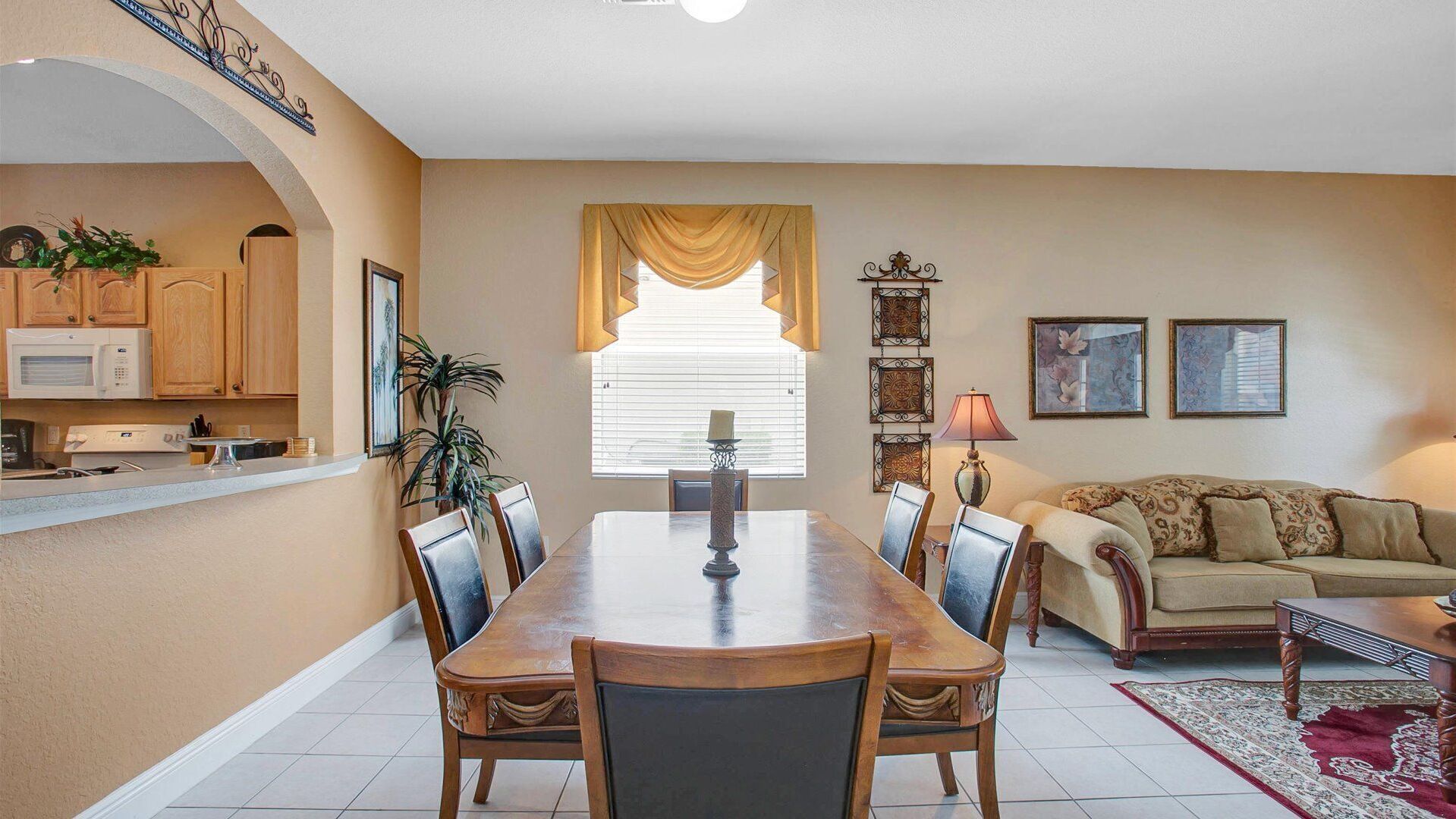 Un coin repas avec une table et des chaises en bois, une cuisine avec des meubles en bois, un canapé et un élément décoratif mural.