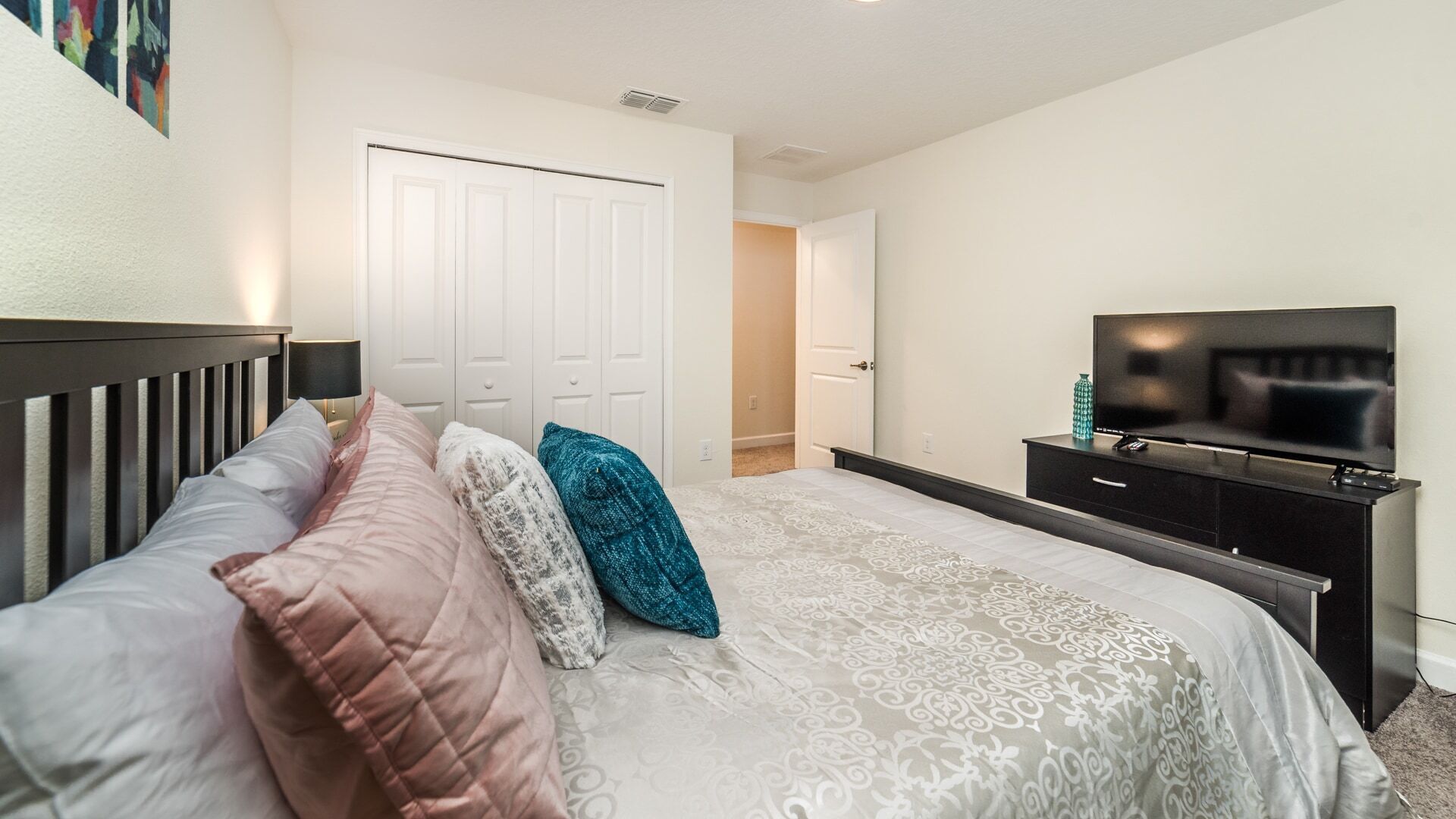 A bedroom with a bed, a TV, and a wardrobe.