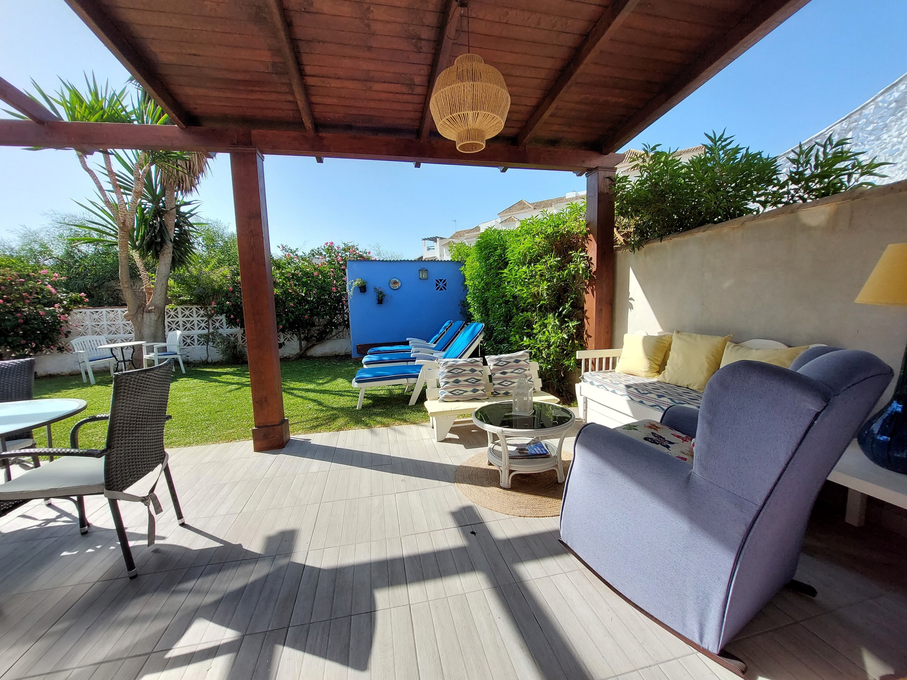 Ein überdachter Patio-Bereich mit Gartenmöbeln, einem Pool und einem Garten.