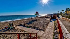 Ein Strand mit einem Rettungsturm, einer Holzpromenade und Palmen.