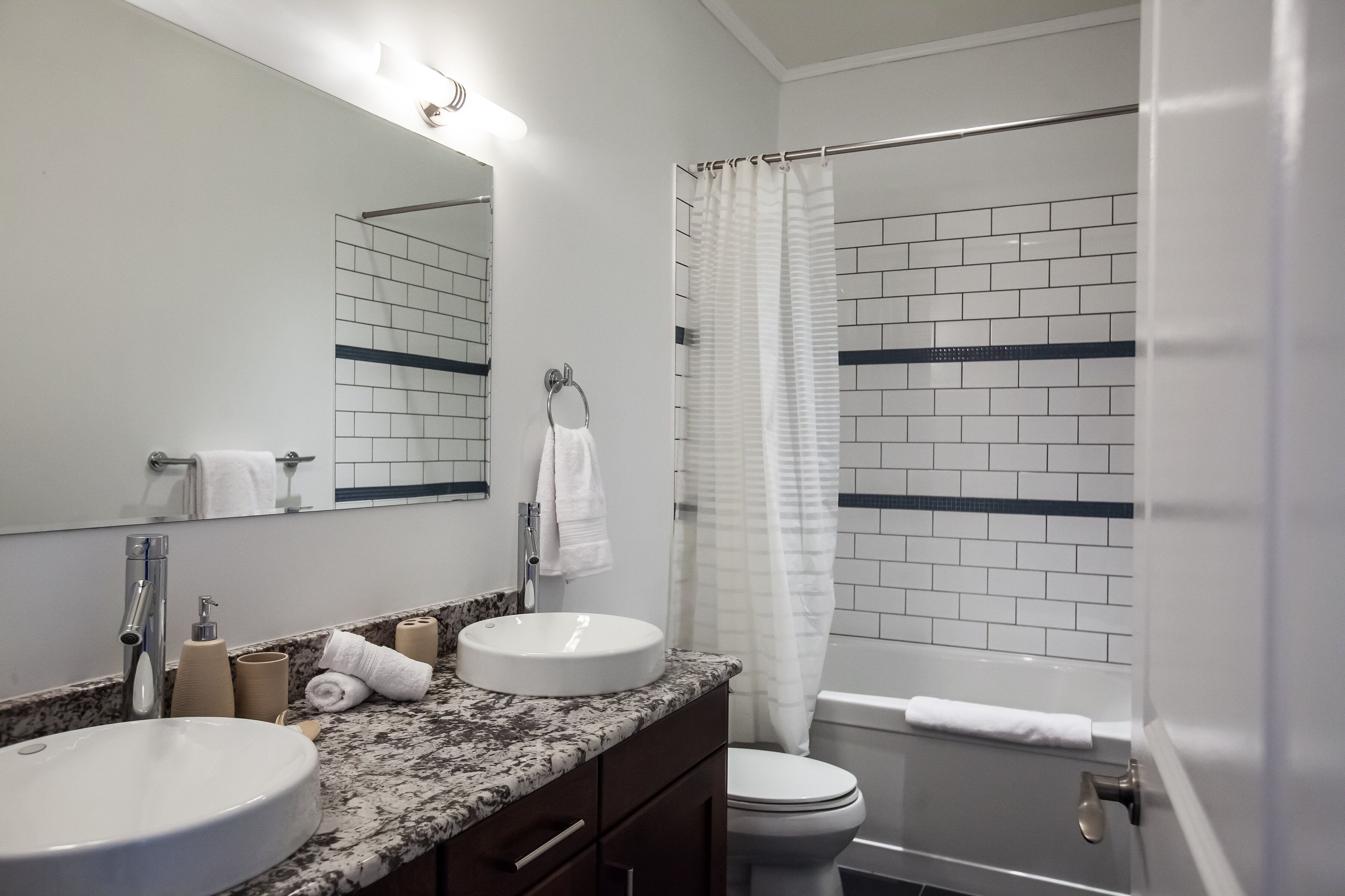 A bathroom with two sinks, a mirror, a bathtub, and a shower curtain.