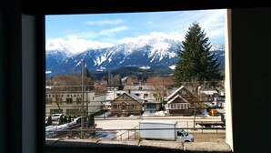 A view of a town with snow-capped mountains in the background, a mix of residential and commercial buildings, and a clear sky. - Alpenglow Penthouse by Revelstoke Vacations (Revelstoke)