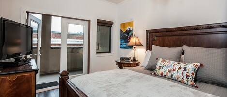 A hotel room with a bed, a television, a lamp, and a painting on the wall.