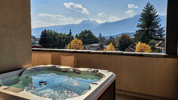 A hot tub with a view of mountains and autumn trees. - Alpenglow Penthouse by Revelstoke Vacations (Revelstoke)