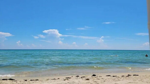 Een strand met helderblauw water en een zandstrand.