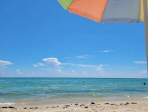 Une plage à l’eau d’un bleu limpide et au rivage sablonneux.