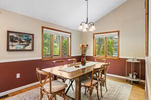 Un coin repas avec une table en bois, des chaises, un lustre et un tableau au mur.